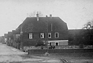 Bild von ca. 1930: Blick vom Altrhein auf das alte Pfarrhaus in der Rheinstraße